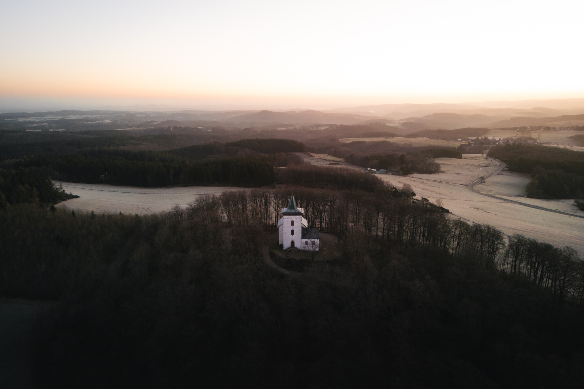 Eifelblick Michelsberg Sonnenaufgang hinter der Kapelle St. Michael im Winter