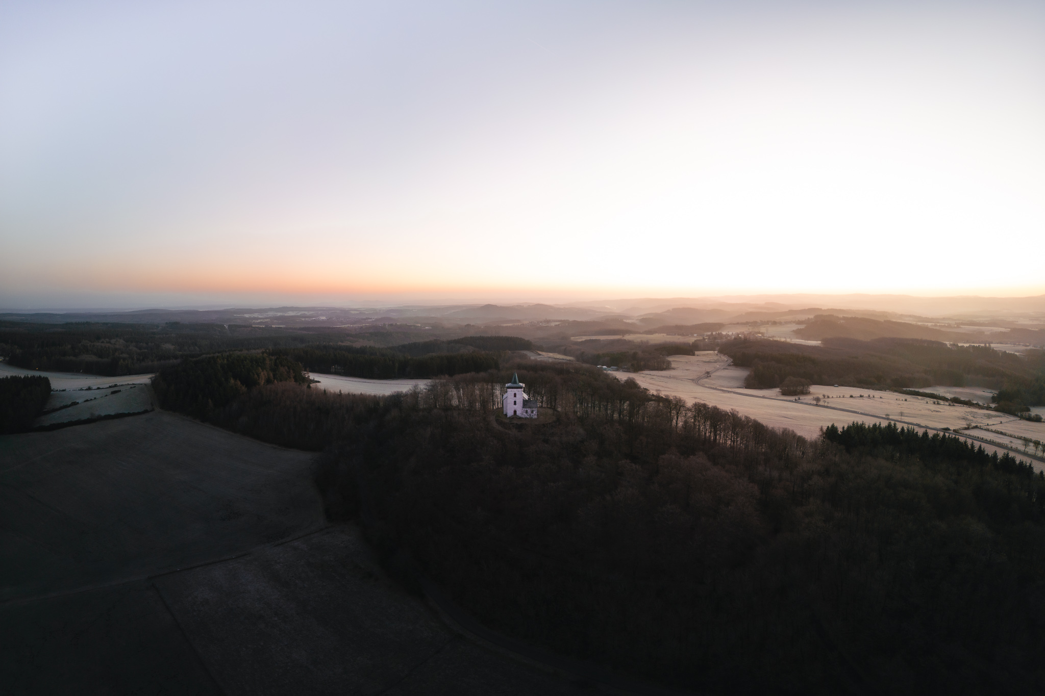 Eifelblick Michelsberg Sonnenaufgang hinter der Kapelle St. Michael im Winter